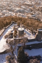 Snowy castle with towers and walls, surrounded by forest and city in the background, Nagold, Calw