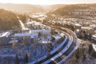 Snowy city landscape with a bridge and roads surrounded by hills and trees, Nagold, Calw district,