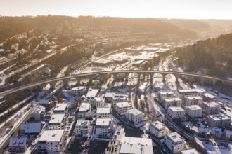 A viaduct over a snowy town with houses, nestled in a hilly landscape, Nagold, Calw district, Black