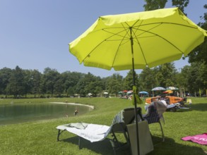 Vacation, umbrellas and sunbeds on the shores of Lake Neubeurer, Bavaria, Germany