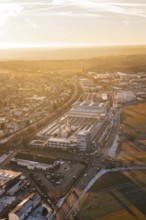 Industrial area and city in winter surroundings, illuminated by sunrise, fields and roads visible,