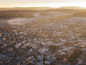 City view in golden light, snowy roofs and wintry hills in the background, Althengstett, Calw