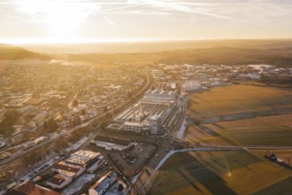 Urban landscape with industrial buildings in bright morning light, fields stretching into the
