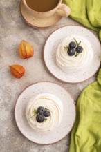 Pavlova Meringue dessert with crisp meringue and blueberry, cup of coffee, on brown concrete