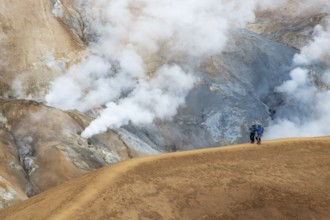 Two tourists walking in the geothermal area of Hveradalir, part of the active Kerlingarfjöll
