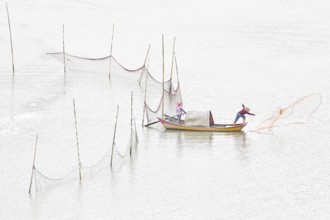Woman and man in a small boat fishing with a net in Xiapu, Fujian Province, along the East China