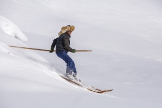 Skier with long traditional wooden skis and a long pole in the Altai Mountains, possibly the