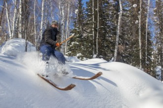 Skier with long traditional wooden skis and a long pole in the Altai Mountains, possibly the