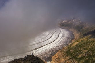 On a foggy day, a tourist observes the largest glacier in the Alps, the Aletsch Glacier, UNESCO