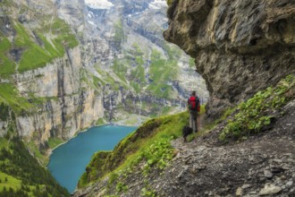 On a summer day, a tourist walks along the panoramic trail with views of Oeschinen Lake