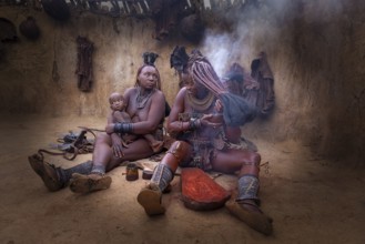 Ovahimba or Himba women, one with a child while another takes a traditional smoke bath, Kaokoland,