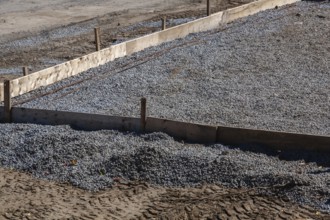 Wooden concrete pouring forms and bed of crushed and compacted stone aggregate to rest concrete