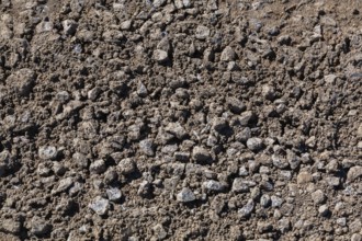 Close-up of sand mixed with grey crushed stone aggregate used to form a bed for constructing roads