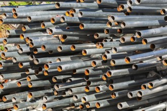 Close-up of stacked heavy duty galvanized steel poles in outdoor storage yard in early autumn,
