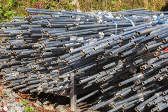 Pile of stacked heavy duty galvanized steel poles in outdoor storage yard in early autumn, Quebec,
