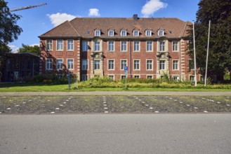 Town hall, brick buildings, flagpoles, façade with windows, dormers, parking boxes, sidewalk,
