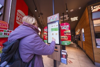 A woman interacts with an ordering machine in a modern fast food restaurant, London, England, Great