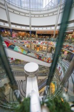 Lively interior of a shopping mall with several escalators and colorful shops, London, England,