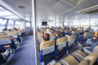 Interior view of a boat with many seated passengers and modern seats, London, England, Great