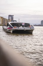 A ship moves on a river with a modern city in the background, London, England, Great Britain