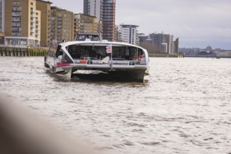 A river with tall modern buildings on its banks, with a ship in the foreground, London, England,