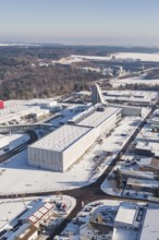 Snowy industrial area with forest in the background, characterized by clear lines and roads,