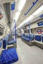 The interior of a subway car with blue seats and signs on the walls, London, United Kingdom