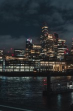 Urban skyline at night with illuminated skyscrapers and reflections in the river, London, England,