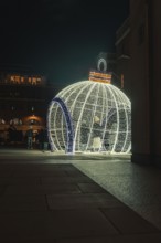 Large glowing Christmas ball on square with people in the evening setting, London, England, Great