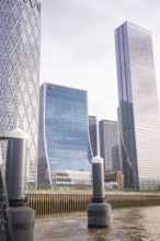 Skyscrapers with glass façade on a river under cloudy sky in the city, London, England, Great