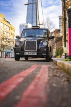 A black taxi against the backdrop of The Shard in London, London, England, Great Britain