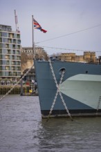 Front view of a ship in water with British flag surrounded by urban architecture, HMS Belfast,