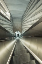 Modern escalator in futuristic architectural setting with people, London, United Kingdom