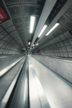 A subway tunnel with escalator and futuristic atmosphere through lighting and architecture, London,