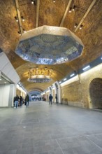 Long tunnel with decorative ceiling and people, warm lighting in an urban setting, London Bridge