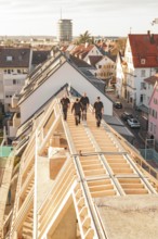 Craftsmen walking on a roof of a new building in an urban environment, carpentry, renovation, roof