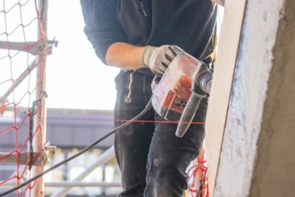 Close-up of a craftsman with a drill on a construction site, carpentry, renovation, roof extension,