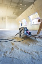 Interior with construction site, a saw lying on the ground under bright light, carpentry,