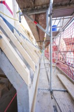 Scaffolding with protective net, view of timber structure and concrete, carpentry, renovation, roof