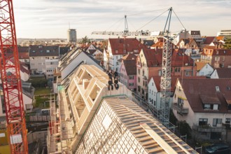 Workers on a half-finished roof surrounded by varied urban development, carpentry, renovation, roof