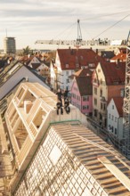Group of workers on a roof in a lively urban environment with a crane, carpentry, renovation, roof