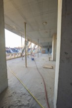 Open interior with construction work, exposed concrete walls and supports, carpentry construction