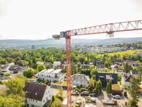 Crane over an urban residential area with green areas and a wide view, construction site of a