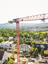 View of a large crane over a residential area in front of a mountainous landscape, construction