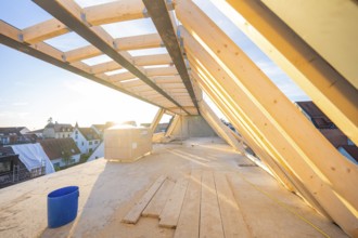 Light-flooded roof truss in the construction process with a bucket on the ground, carpentry