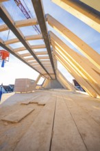 A wooden roof truss with an open sky above. Construction work is in progress, carpentry