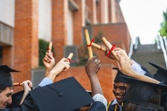 Diverse group of university students wearing graduation caps and gowns, celebrating their