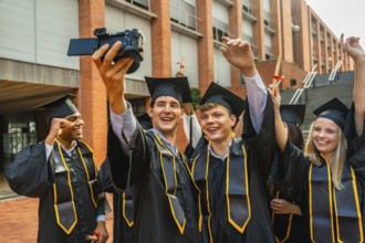 Diverse group of young university graduates in caps and gowns celebrating success, smiling and