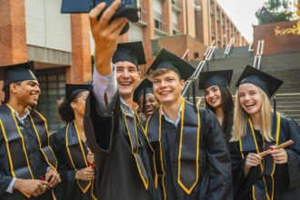 Group of smiling diverse students graduating from university, wearing academic caps and gowns,