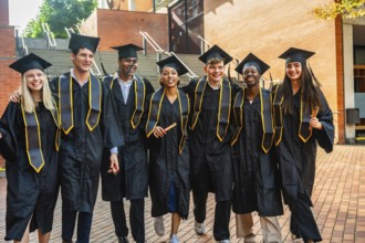 Diverse group of young adult students celebrating their university graduation, proudly wearing